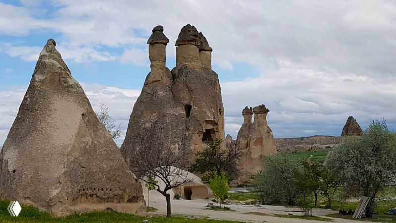 Панорама с верхней точки на долину, где видны редкие посадки растений, тропы и характерные конусообразные скальные образования.