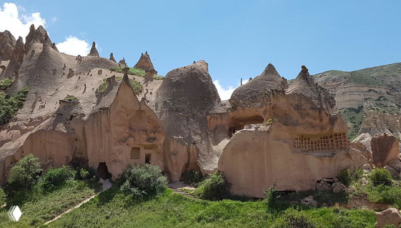Резные ниши и фасады пещерных жилищ в Каппадокии, хорошо видны отверстия и структуры, высеченные в мягкой вулканической породе под солнцем.