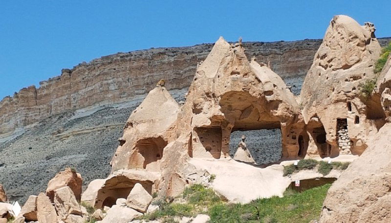 Пещерные арки и окна в пористой скале, видны проходы и уступы долины; свет подчёркивает текстуру породы и форму выемок.