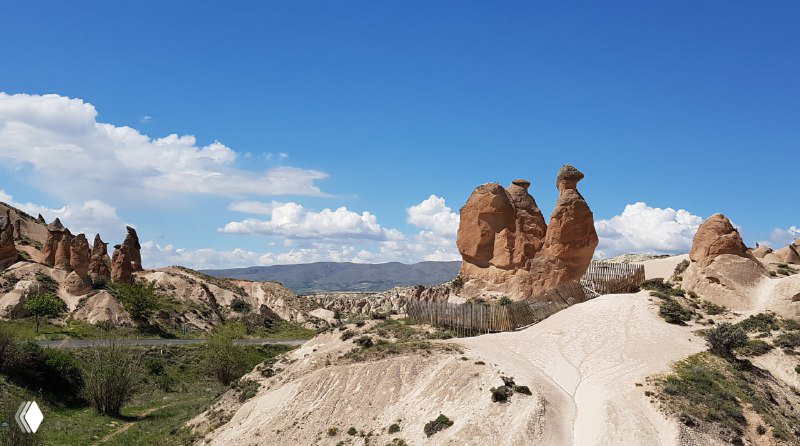 Ландшафт долины Деврент с округлыми каменными фигурами, среди которых выделяется форма, напоминающая каменного верблюда на фоне тропы.