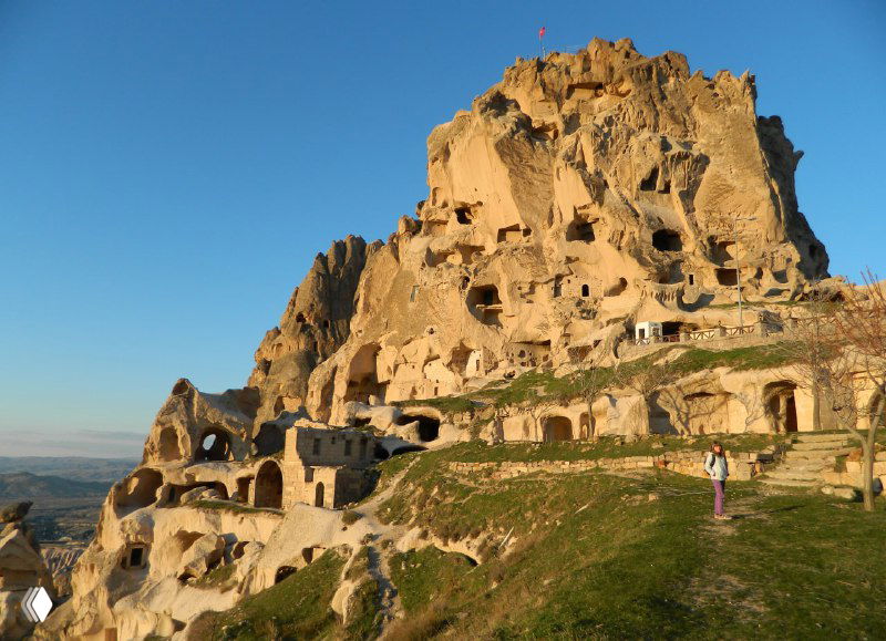 Крупный план крепостного конуса Учхисара с видимыми отверстиями и вырубленными жилыми зонами на солнечном склоне.