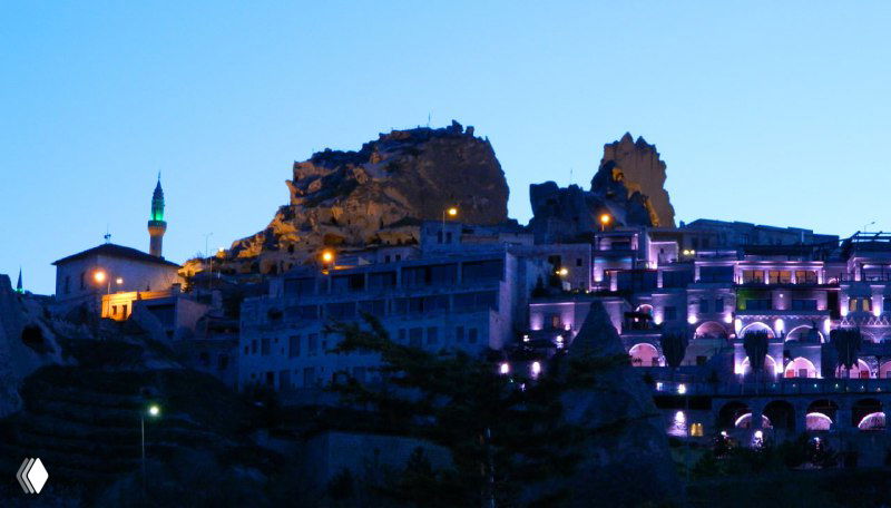 Ночная подсветка в Учхисаре: туфовые дома и современные строения у подножия крепости, подсвеченные вечером.