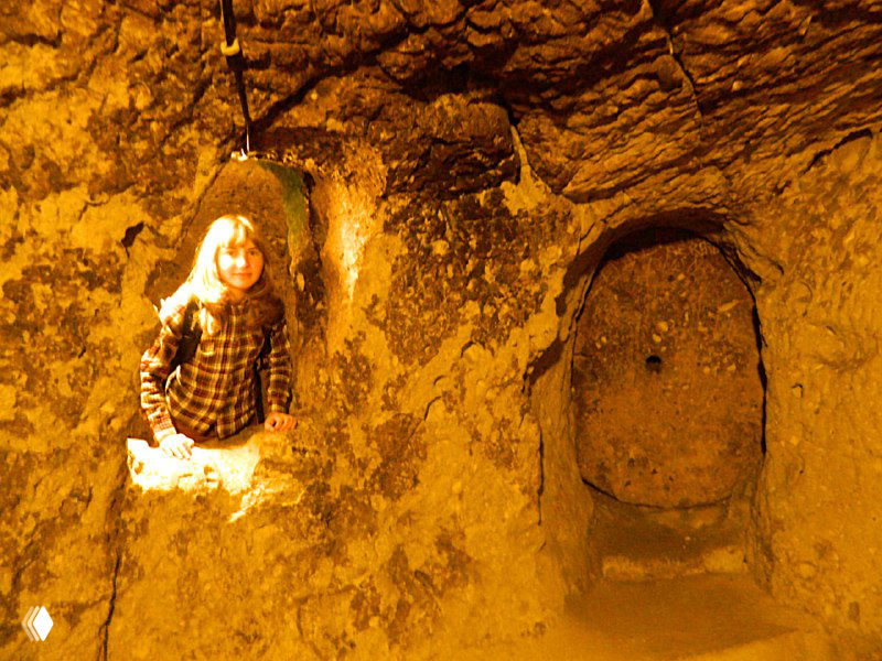 Человеческая фигура в нише подземного жилища рядом с каменной дверью; показывает масштабы помещений и бытовые зоны Деринкую.