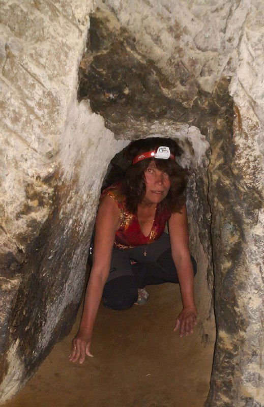 Человек с налобным фонарём проходит через узкий туннель в монастыре Кешлик, показывает масштаб проходов и необходимость осторожности при осмотре пещер.