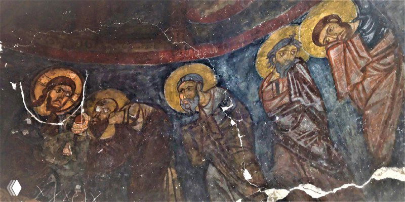 Группа святых и апостолов на фреске Кешлик: выраженные лица, нимбы и позы видны несмотря на копоть и износ, сохраняются цветовые акценты росписи.