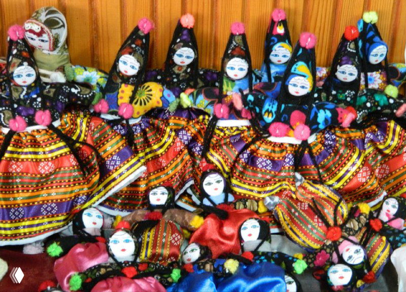 Яркие тканевые куклы-сувениры Соганлы на полке: множество разноцветных лоскутных кукол в традиционных нарядах.