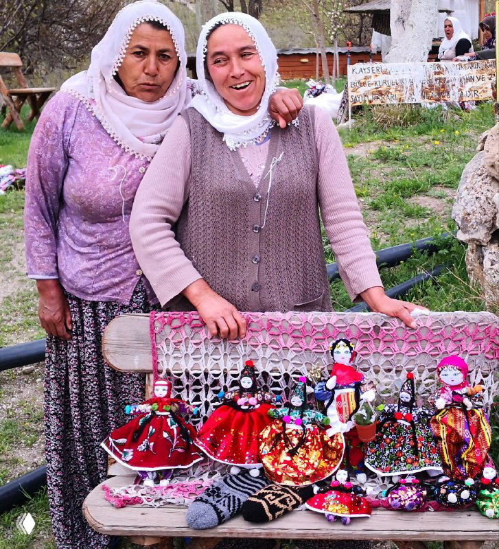 Местные мастерицы в традиционной одежде продают лоскутные куклы на ярмарке в Соганлы, улыбки и домашняя атмосфера.