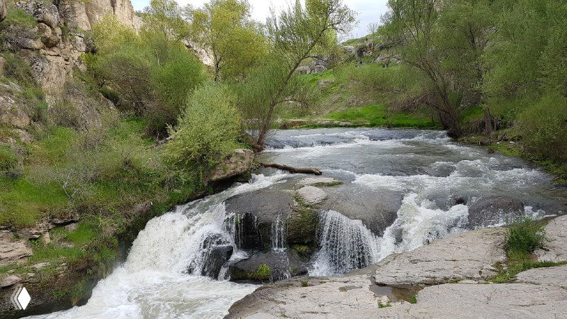 Разливы и небольшие водопады реки Мелендиз в узкой части каньона Ихлара, зелёные кусты и каменные пороги на переднем плане