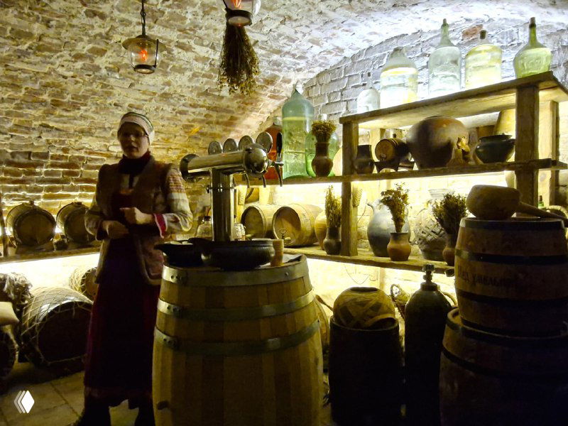 Подвальная экспозиция с бочками, старинными сосудами и стеклянными банками в музее медовухи, атмосфера темного винного погреба