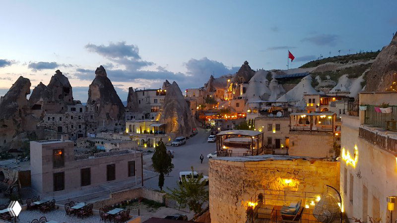 Ночной панорамный вид на центр Гёреме с освещёнными улицами и террасами пещерных отелей, уютная вечерняя сцена города.
