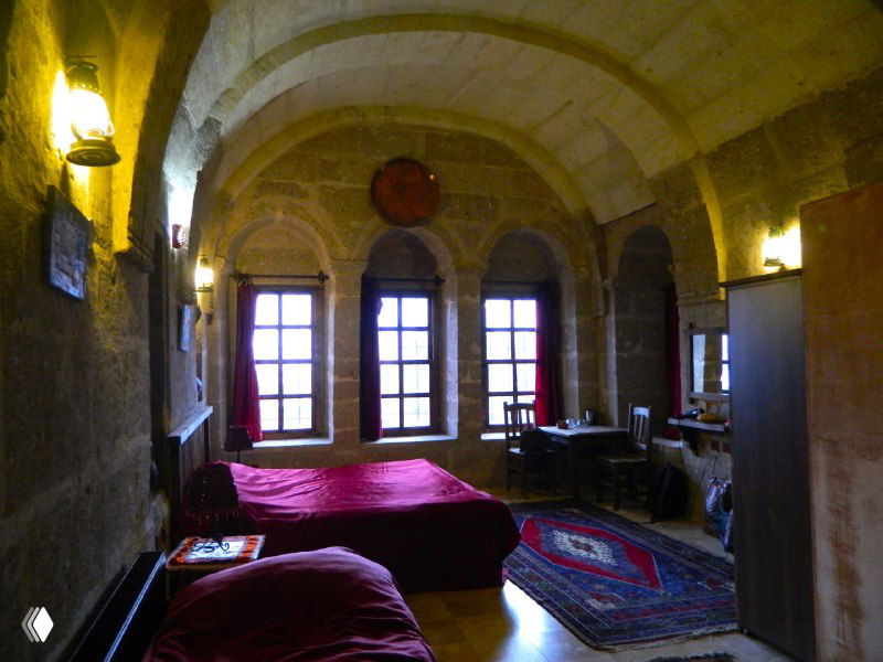 Большой пещерный зал с арочными окнами и высокими потолками в стиле греческого особняка, демонстрация альтернативных типов жилья в регионе.