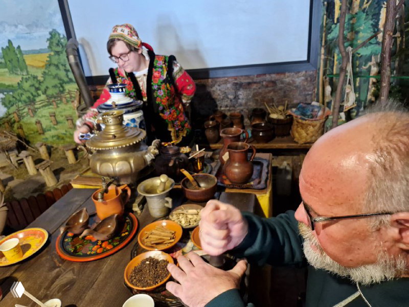 Показ приготовления сбитня: самовар, специи и посетитель, который толчет пряности, стол с посудой и ингредиентами