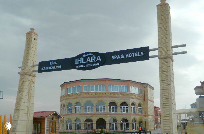 Входная арка и фасад современного термального отеля в Каппадокии с надписью и парковочной зоной у входа, пример SPA-варианта размещения.