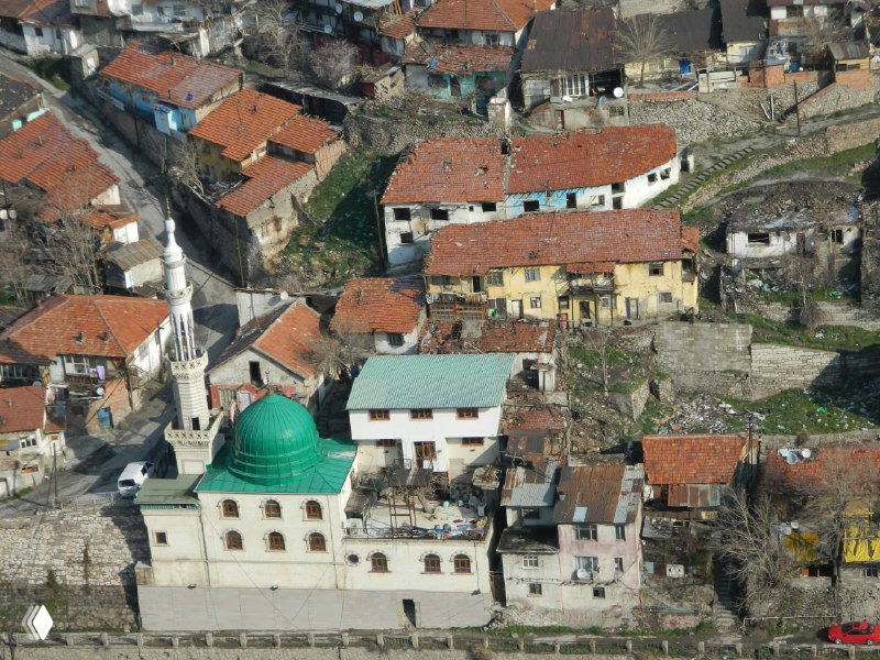 Вид с высоты на старинный район с мечетью в зелёным куполом и плотной застройкой — кадр с пути из Анкары в Каппадокию.