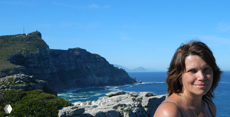 Автор фотографии у обрыва с видом на океан и мысы вдали — человек на переднем плане и широкий океанский горизонт за ним.