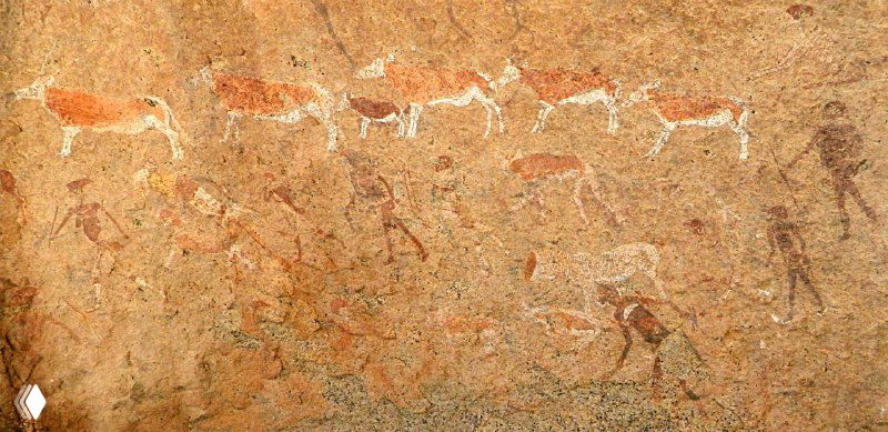 Широкий участок настенной росписи «Белая леди»: множество фигур людей и животных, снова видны контрасты охристых и белых пигментов на камне.