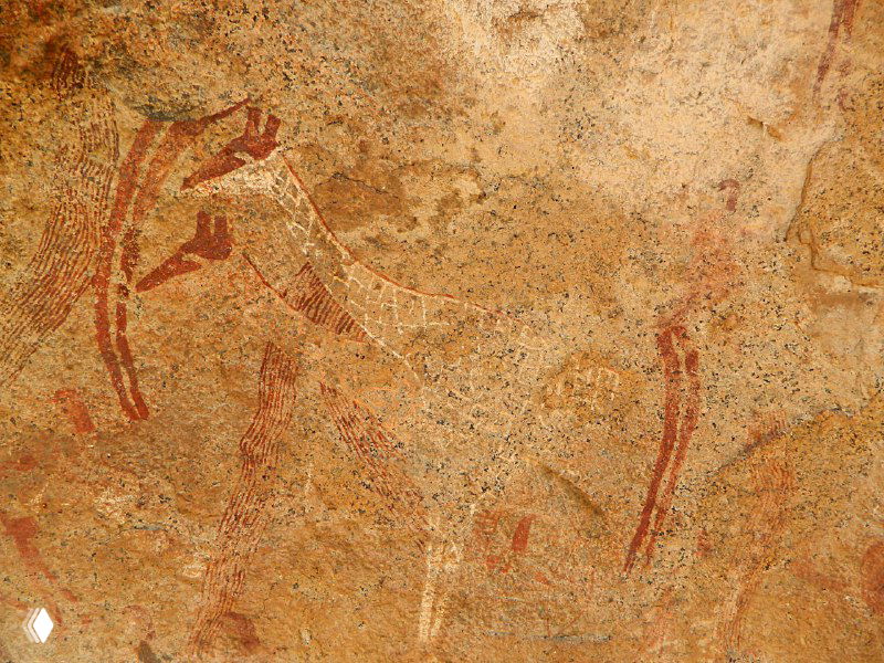 Крупный план старинной росписи: красные и белые линии, стилизованные изображения и декоративные элементы, хорошо заметны авторские мазки.