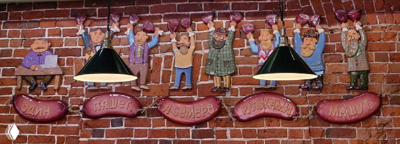 Кирпичная стена с декоративными вывесками и фигурами над барной зоной; элементы декора в стиле традиционного бистро.