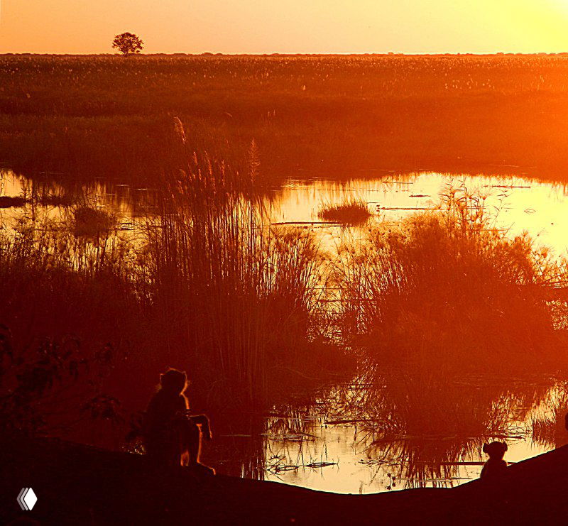 Закат над заливом реки Линьянти: оранжевые тона, отражение в воде и силуэты людей на берегу создают атмосферу окончания дня.