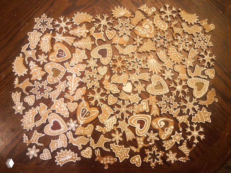 Разложенные на столе расписные маленькие пряники: сердечки, снежинки и фигурки, украшенные белой глазурью и готовые к упаковке.