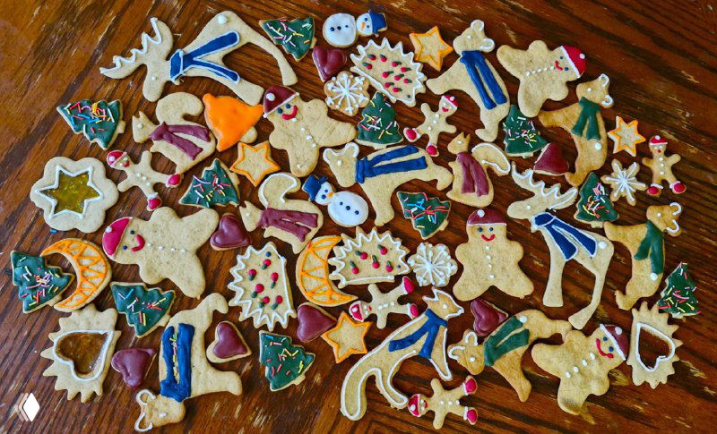 Разноцветные росписные пряники в разных формах на деревянном столе: яркие краски, глазурь и разнообразные контуры для подарков.