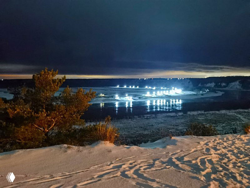 Вид с высокого берега Иртыша на замёрзшую реку и светящиеся огни противоположного берега, зимний пейзаж у Абалакского монастыря