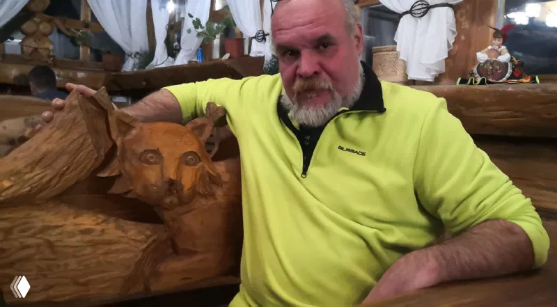 Резная деревянная фигура и мужчина в кафе комплекса «Абалак»: интерьер с плотной резьбой, тёплая атмосфера и детали народного декора