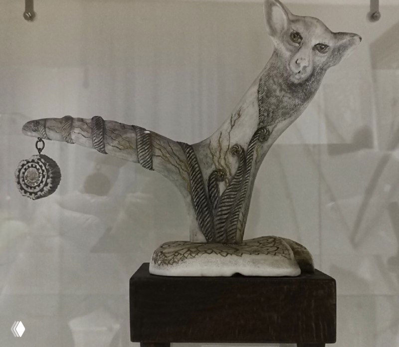 Резное украшение в виде стилизованного животного с удлинённым телом и подвеской, демонстрация орнаментации и мелкой отделки на музейной витрине в Тобольске.