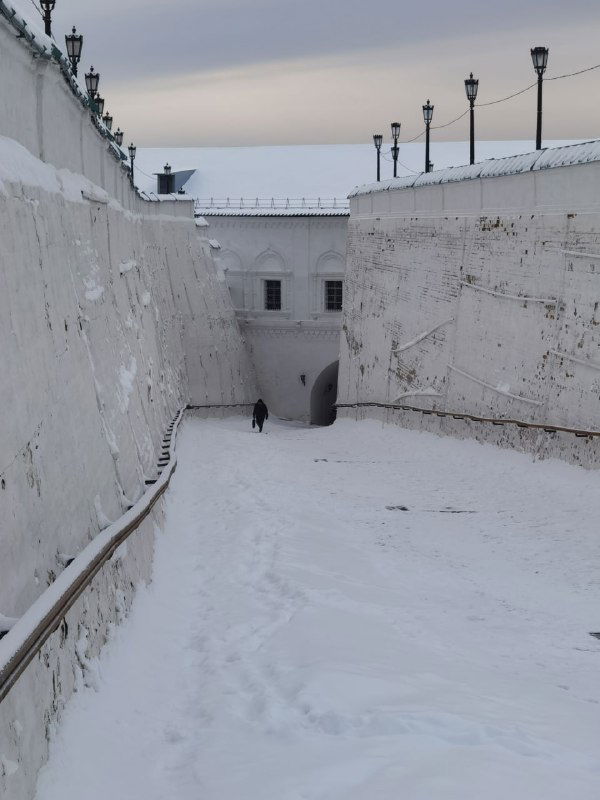 Крутой Прямский взвоз зимой: глубокий овраг с каменными стенами, заснеженной тропой и видимой внизу выемкой между историческими постройками.