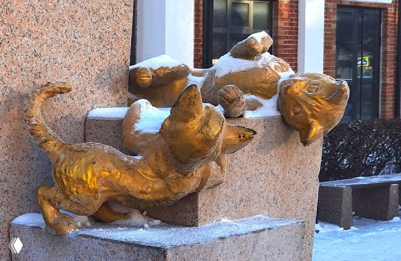 Групповая композиция из отлитых котов и котят на гранитном постаменте в Тюмени, крупный план с деталями поз и снега на скульптурах.