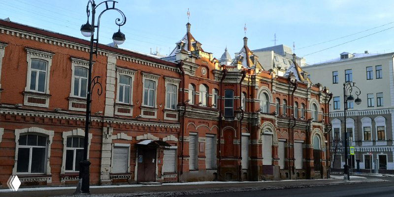 Нарядный кирпичный особняк с декоративными элементами фасада в центре Тюмени, архитектурные детали в дневном освещении.