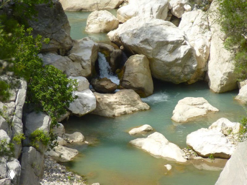 Крупные валуны и мелкие водопады в каньоне Гёйнюк: бирюзовые плесы между белыми камнями на фоне скалистых стен.