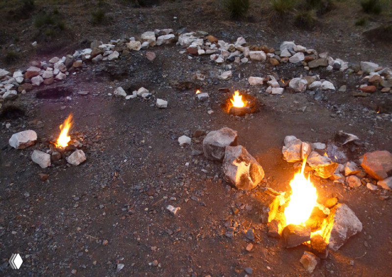Негаснущие огни Химеры: группы языков пламени, выходящих из земли в вечерних условиях среди камней и обломков.