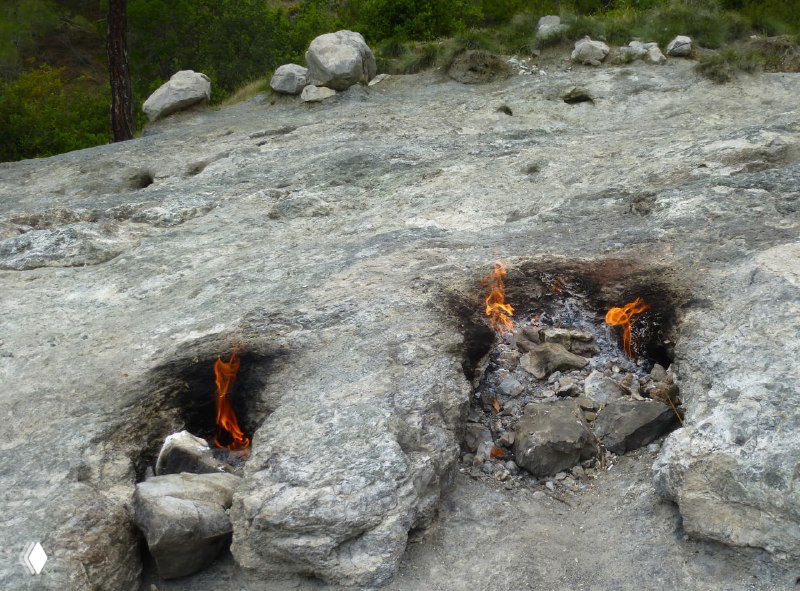 Расщелины в известняковых плитах с голубыми огоньками пламени, выходящими прямо из породы на поверхности Янарташа.