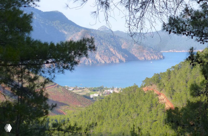 Вид с горной тропы на бухту и посёлок Адрасан внизу, зелёные леса и береговая линия — место завершения дневного перехода.