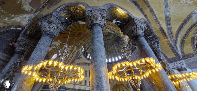 Резные колонны и подвесные светильники в центральной части собора Святой Софии; видны детализированные орнаменты и фактура мрамора на ближних планах.