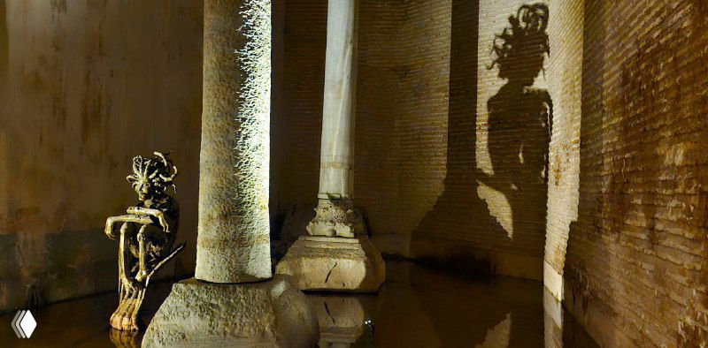 Колонны и тени в цистерне: крупный план основания колонн и их отражений в стоячей воде, добавляющих глубины кадру.