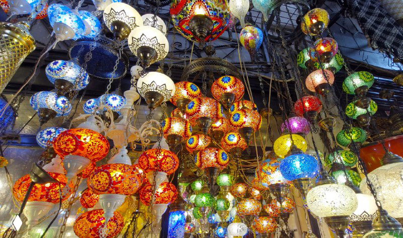 Плотная гирлянда из разноцветных мозаичных светильников, множество форм и узоров висят под куполом торгового зала на базаре Стамбула.