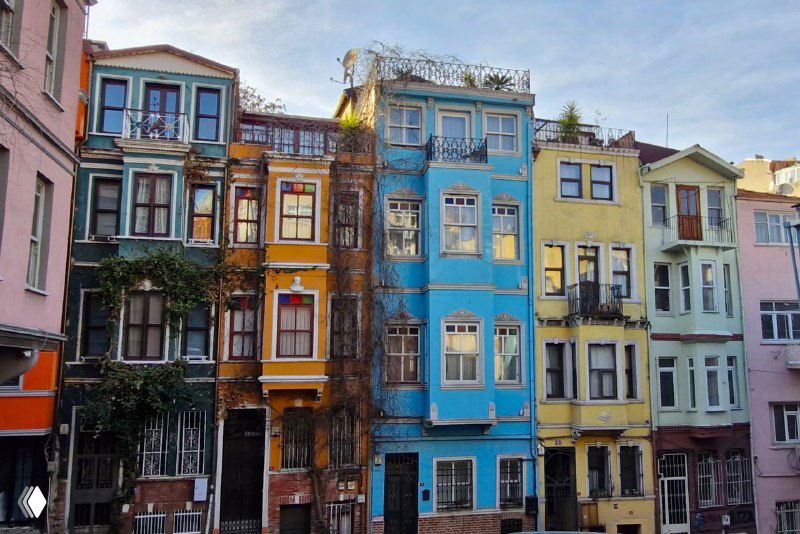 Ряд ярких фасадов старых домов в Балате с эркерами, балкончиками и фактурной окраской в насыщенных тонах