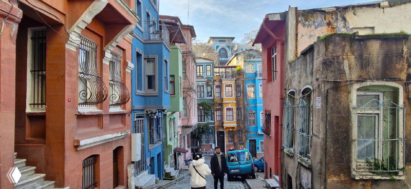 Узкий извилистый переулок в Балате с разноцветными домиками и небольшим количеством прохожих в мягком дневном свете