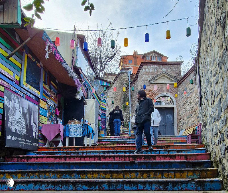 Ярко раскрашенные ступеньки и подвесные фонарики над входом в художественную или сувенирную часть района — атмосферный городской кадр