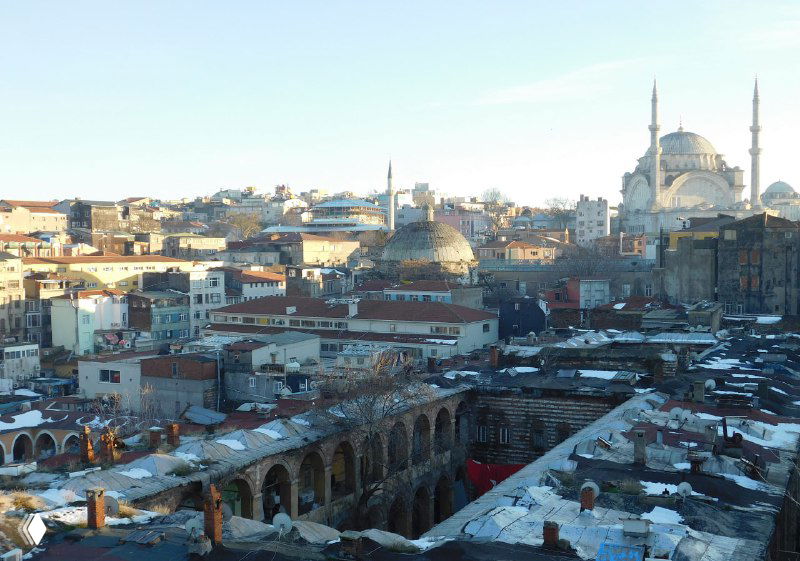 Общий вид на куполообразные выступы, крыши и памятники Стамбула с легким снежным налетом и чередой старых зданий вокруг Гранд Базара.