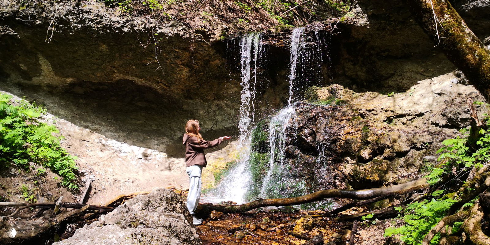 Человек среди ветвей яблони в полном цвету: портрет в облаке белых цветков на фоне плотной зелени кустов и деревьев.