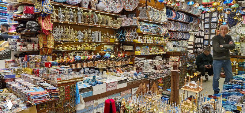 Лавка с керамикой и сувенирами: расписные тарелки, чаши и металлические изделия на полках, типичный ассортимент турецких сувенирных магазинов.