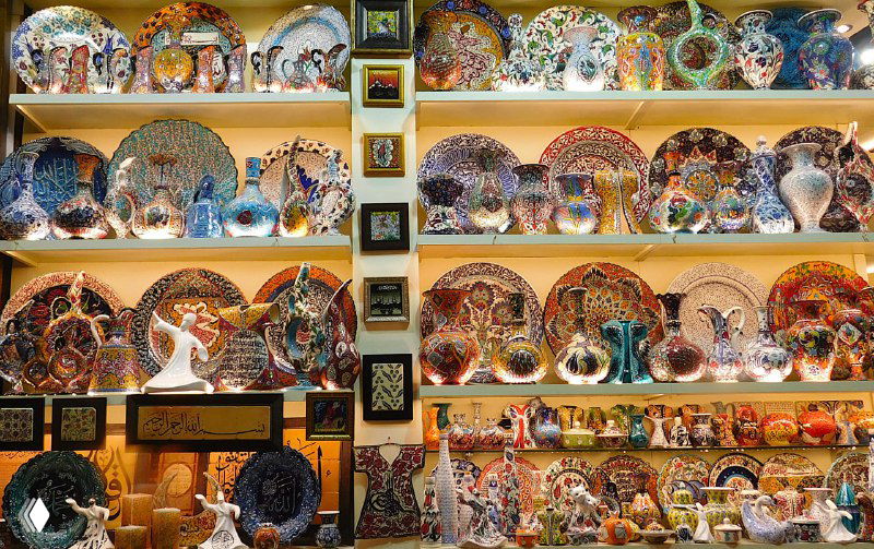 Полки с расписной посудой: тарелки и чаши с традиционными узорами, аккуратно выставленные в ремесленной лавке на рынке Стамбула.