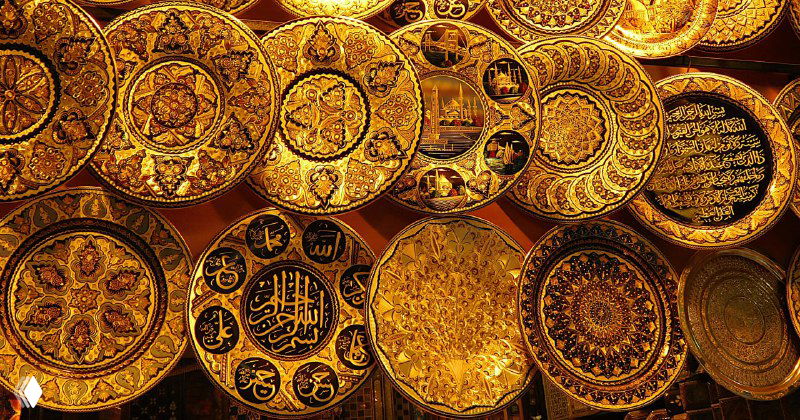 Золотистые декоративные тарелки и медные изделия: блестящие орнаментированные пластины и металлические сувениры на прилавке.