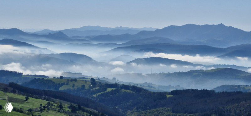 Утренние туманы над долинами и холмами вдоль Камино: мягкие слои облаков над ландшафтом и очертания гор на горизонте.