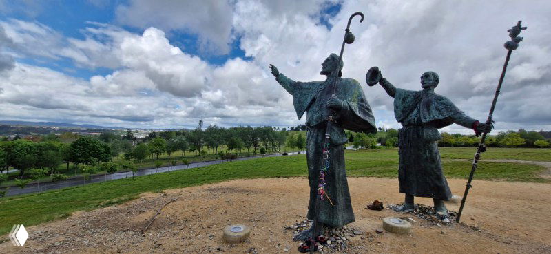 Скульптурная композиция пилигримов с посохами на холме — памятник или ориентир для тех, кто идёт по Камино, с видом на окрестности.