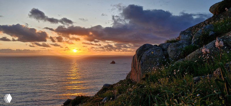 Закат над океаном и скалами на побережье Галисии — тёплые цвета неба и море, завершающий кадр пейзажного маршрута Камино.