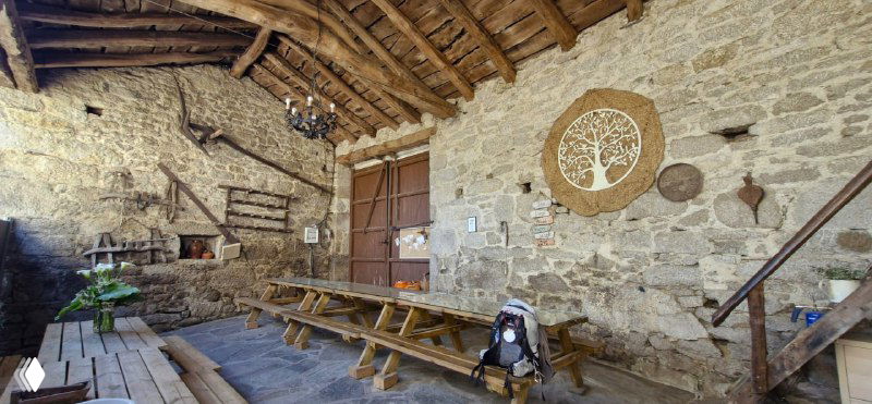 Внутреннее помещение старинного каменного приюта с длинными деревянными скамьями и таблицами — общий зал для встреч и приёма пищи.